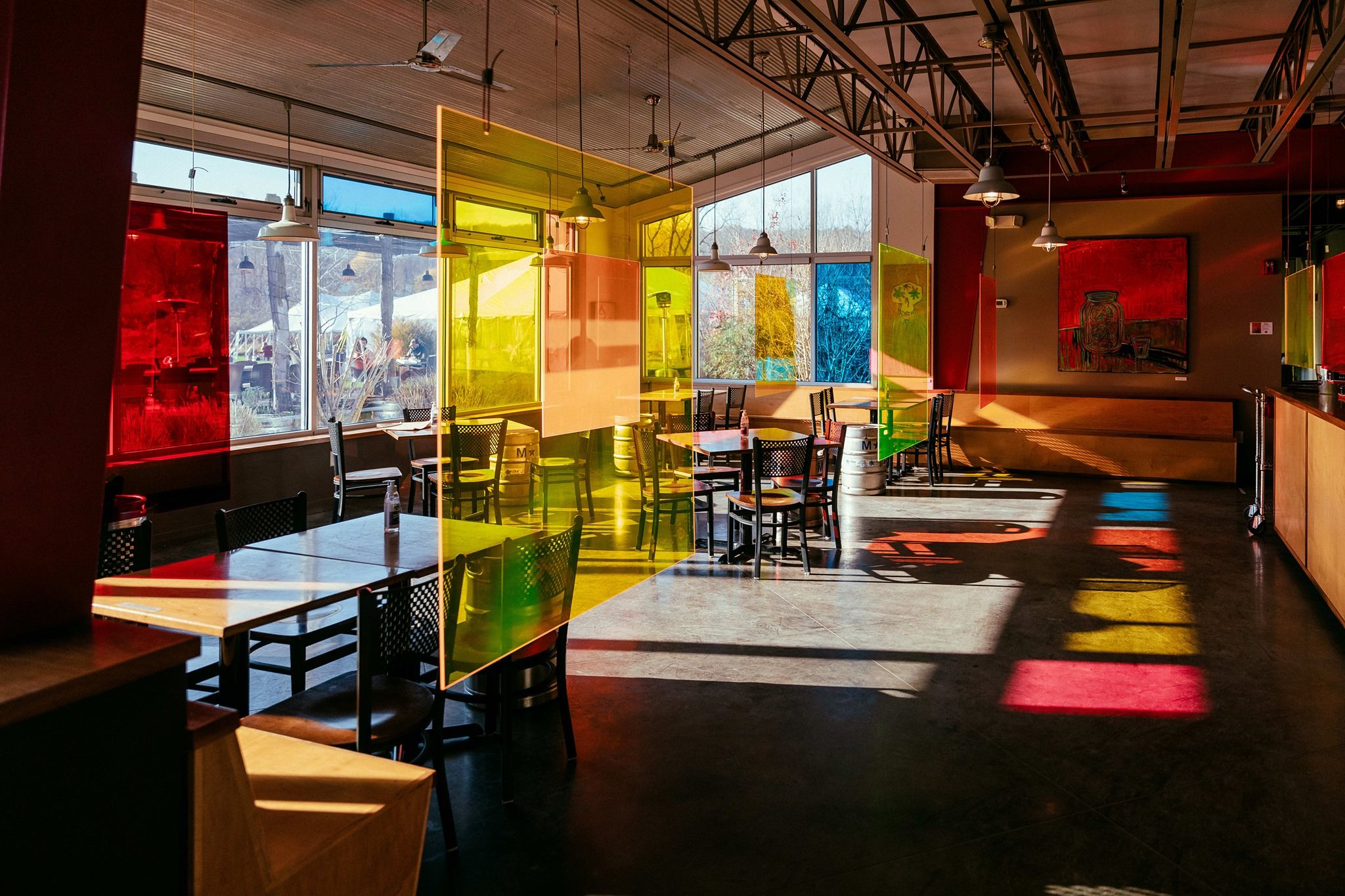 The interior of Ithaca Beer Co. features colorful glass panels, natural light, and an open dining area. The modern design creates a lively and creative atmosphere for beer lovers.
