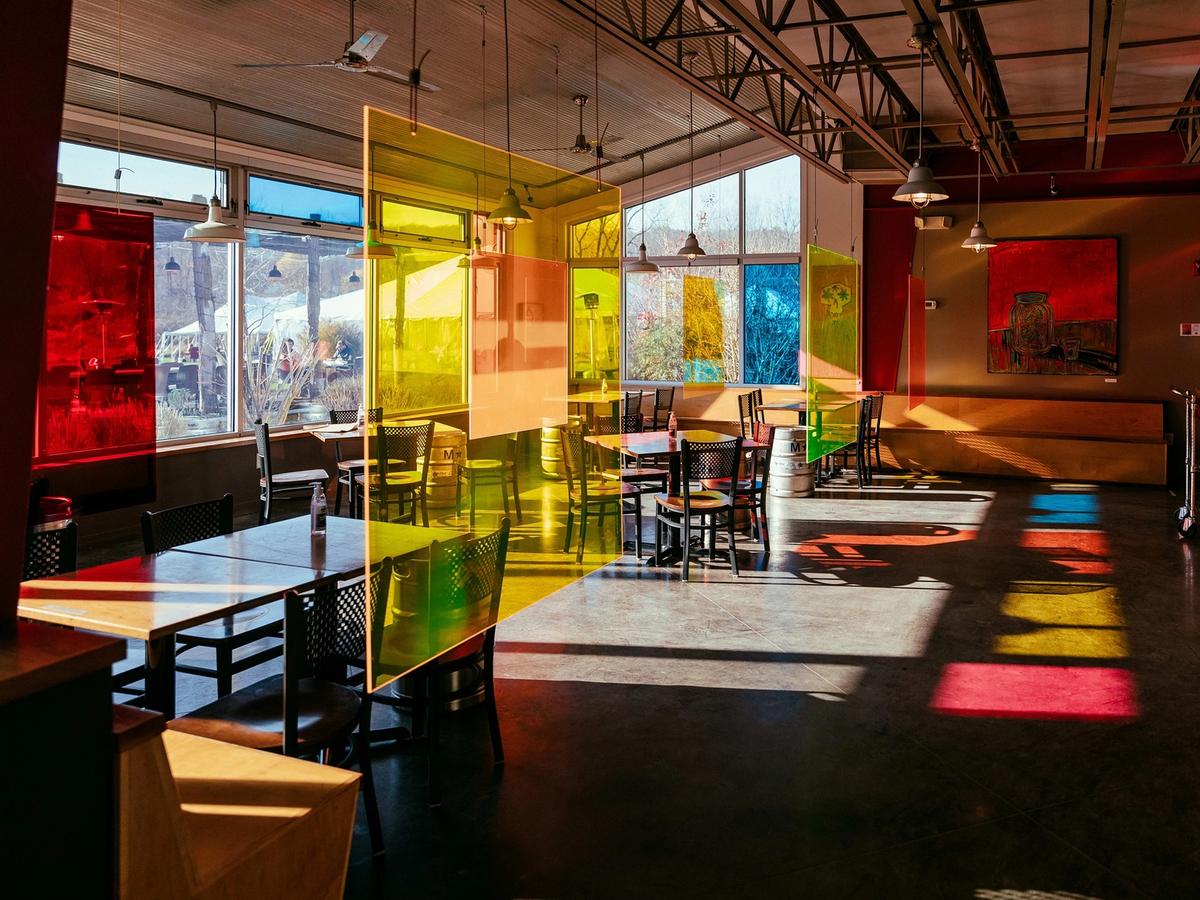 The interior of Ithaca Beer Co. features colorful glass panels, natural light, and an open dining area. The modern design creates a lively and creative atmosphere for beer lovers.