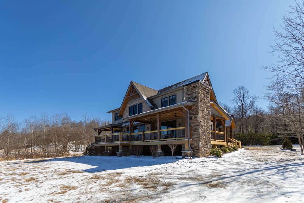 Exterior of mountain home with stone chimney and snow on the ground