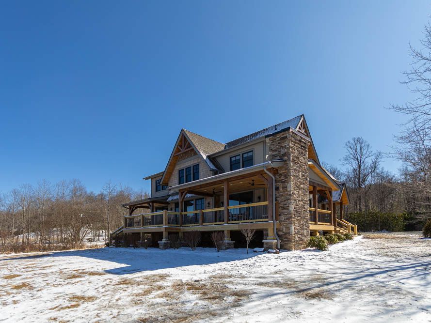 Exterior of mountain home with stone chimney and snow on the ground