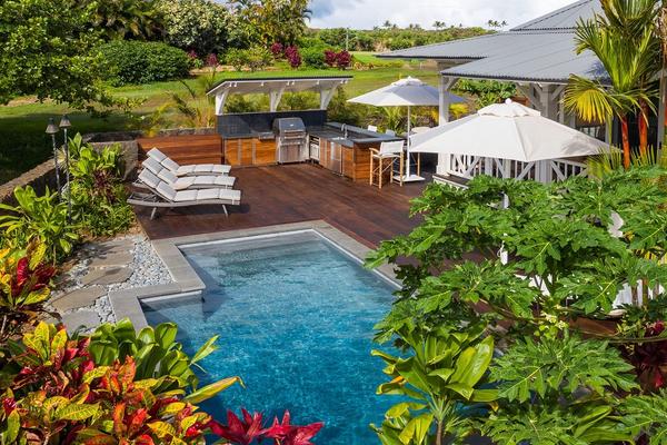 Vacation rental backyard with private pool and lounge deck with white umbrellas
