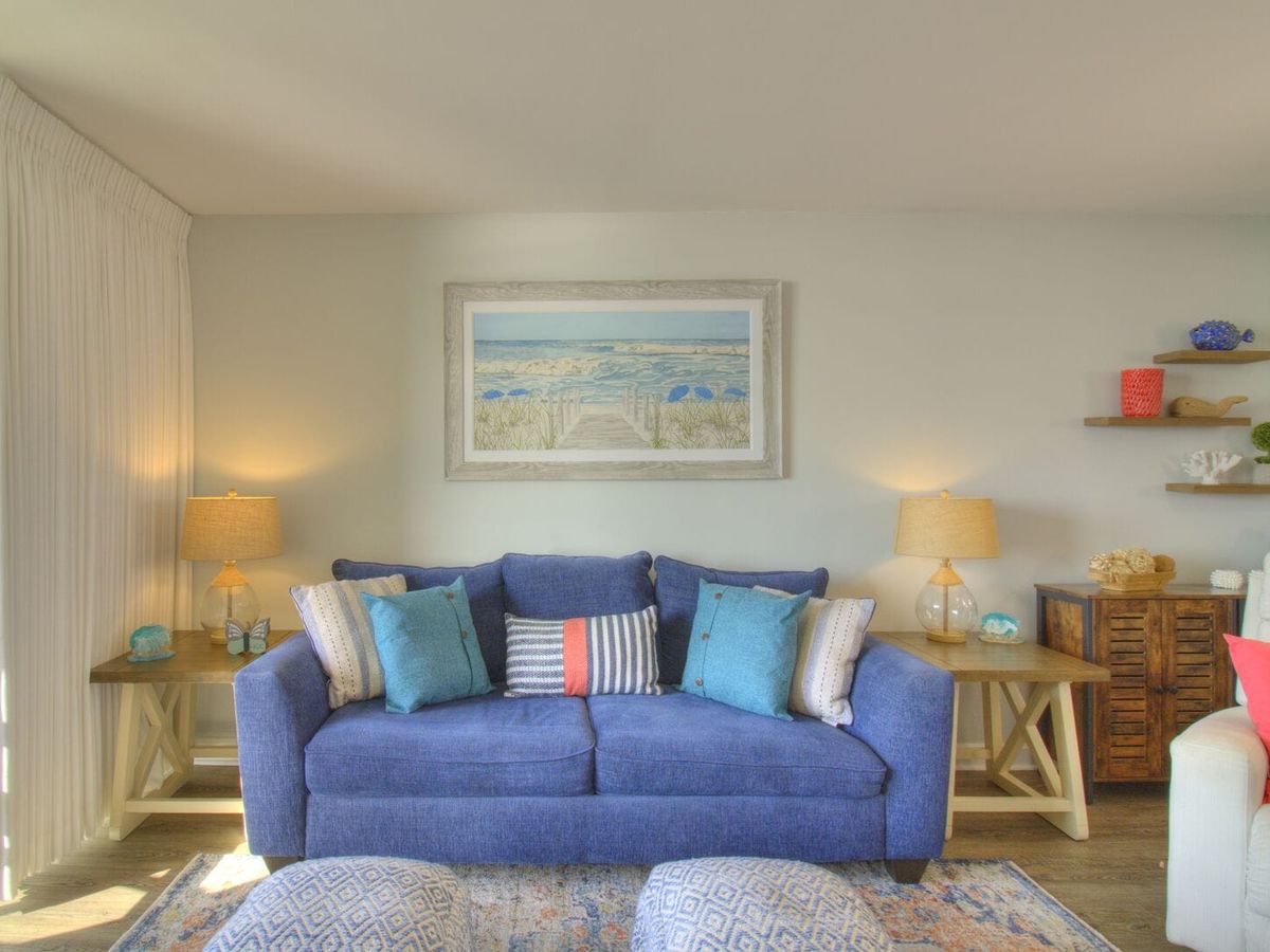 Cozy and cheerful beach condo with a bold blue couch, ocean art, and soft lighting that makes you feel right at home. Perfect for couples or a small family who want a peaceful stay by the shore.