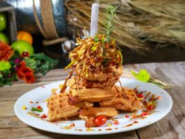 Towering chicken and waffles drizzled with syrup and garnished with herbs at Hash House A Go Go. A playful take on Southern comfort food with a modern twist.