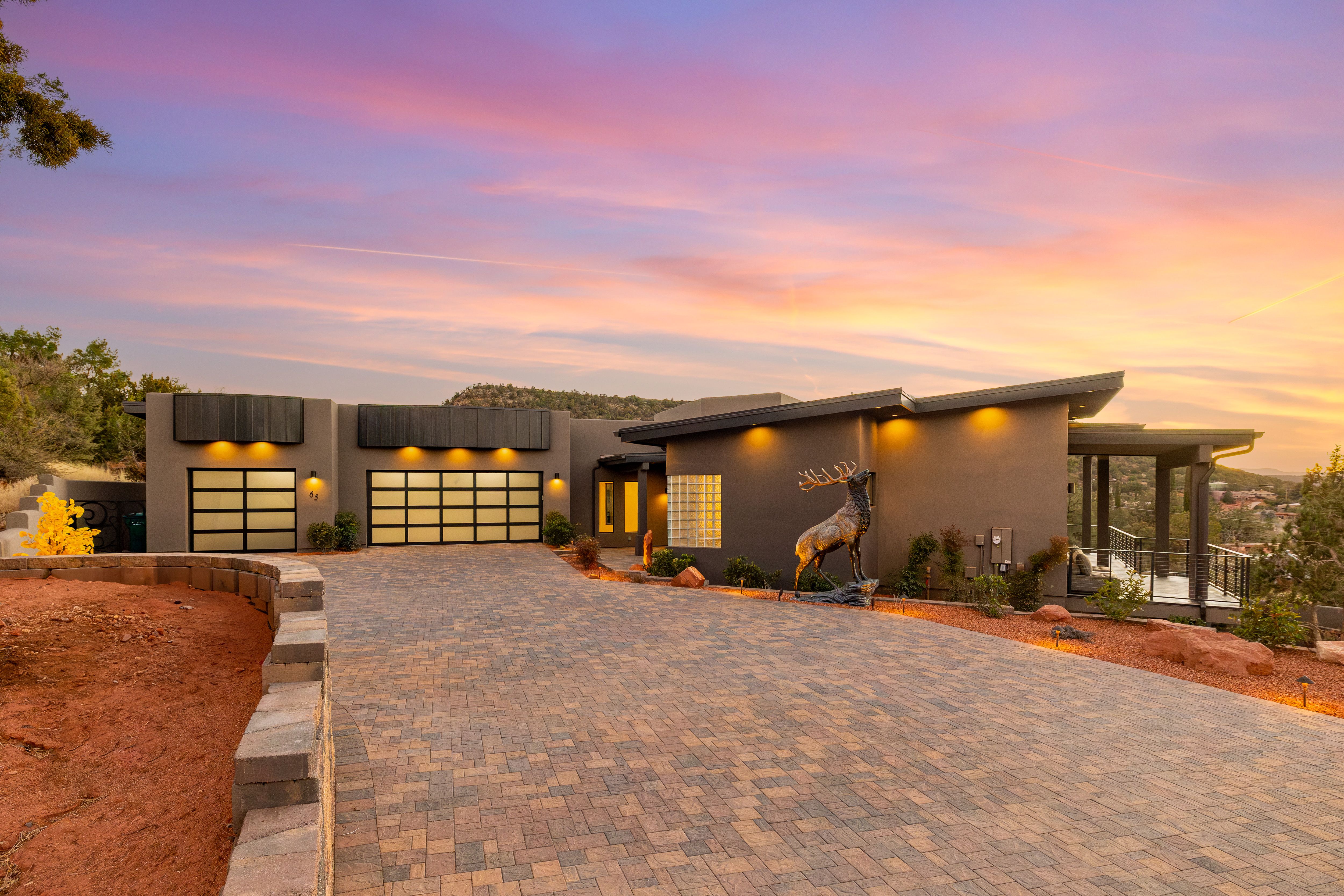 Grey and black house in arizona with moose statue in the front and sunset going down in the background