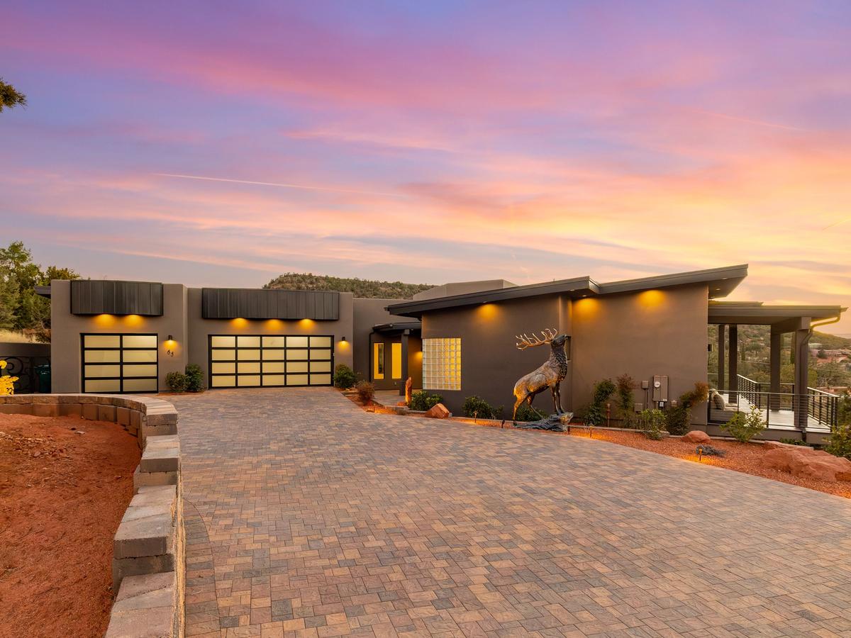 Grey and black house in arizona with moose statue in the front and sunset going down in the background