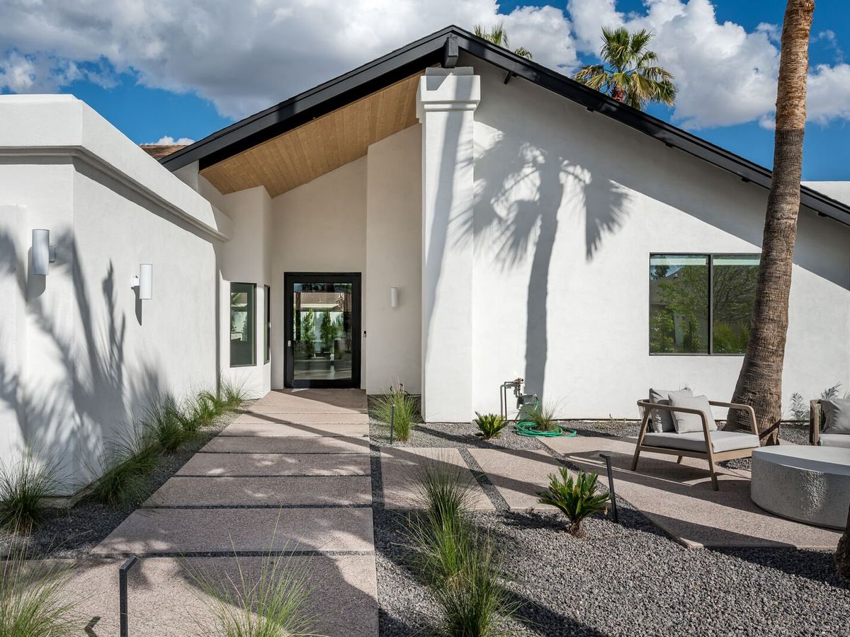 Entryway to white home with door that looks into the home and plants surrounding the walkway