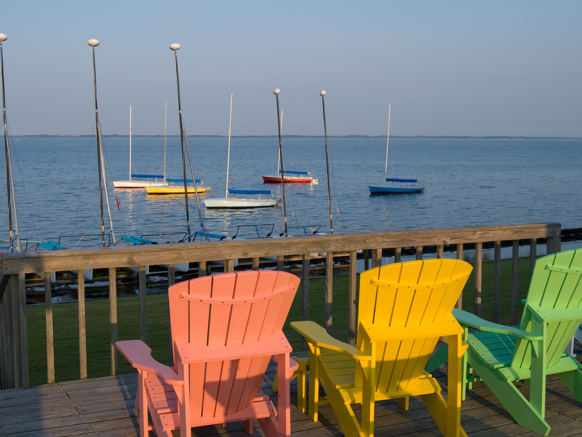 Colorful Chairs on Dock in the Outer Banks Looking Out Towards Boat on Water