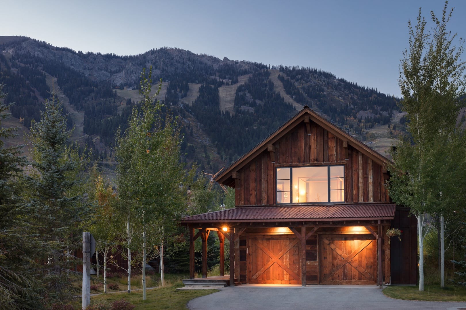 Luxury cabin with mountains in the background and trees surrounding home