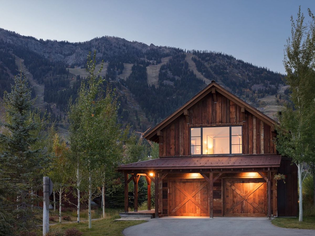Luxury cabin with mountains in the background and trees surrounding home