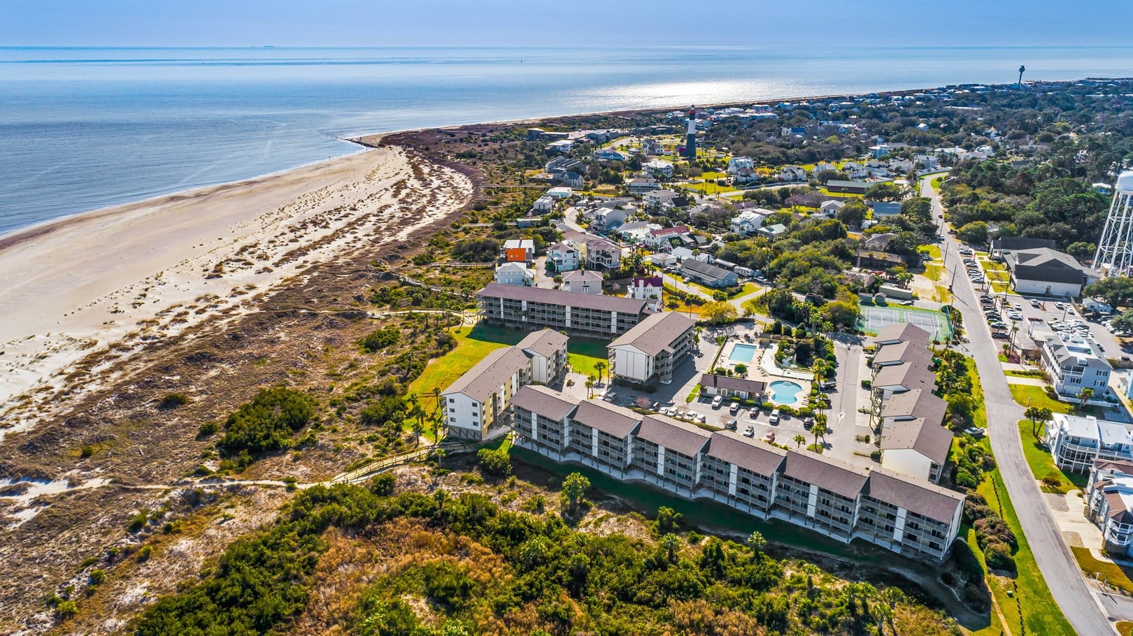 An aerial view of Tybee Island shows sandy beaches, quiet neighborhoods, and a beautiful stretch of coastline. You can see the dunes and water meeting under the bright sun. It’s a peaceful coastal scene that feels calm and inviting.