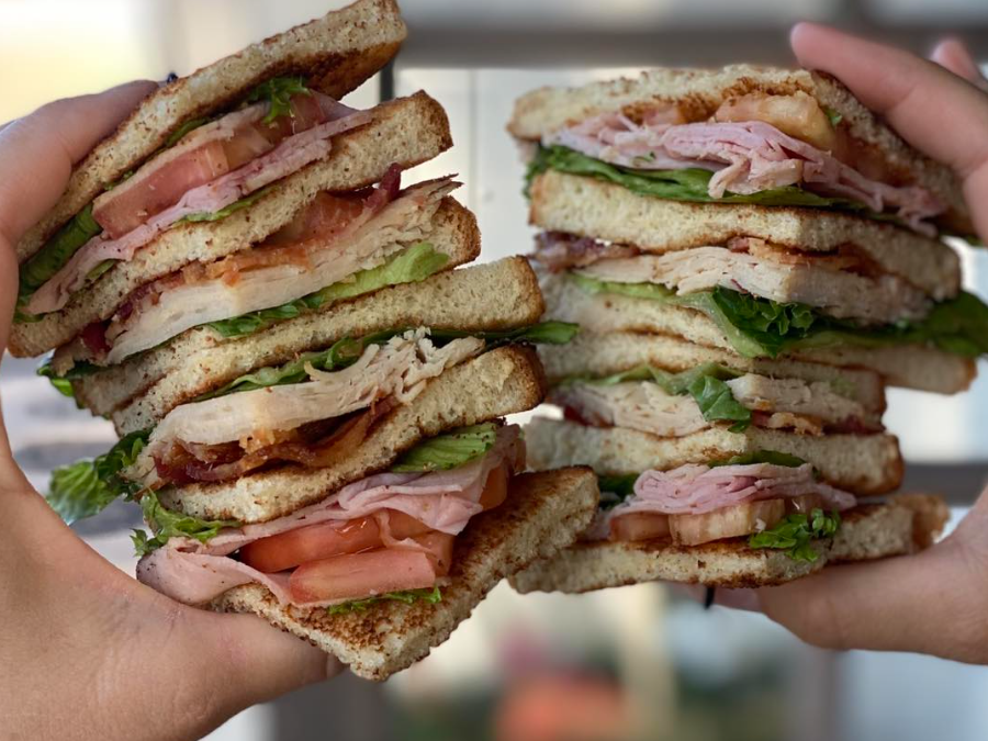Club sandwich cut in two halves with hands in both halves