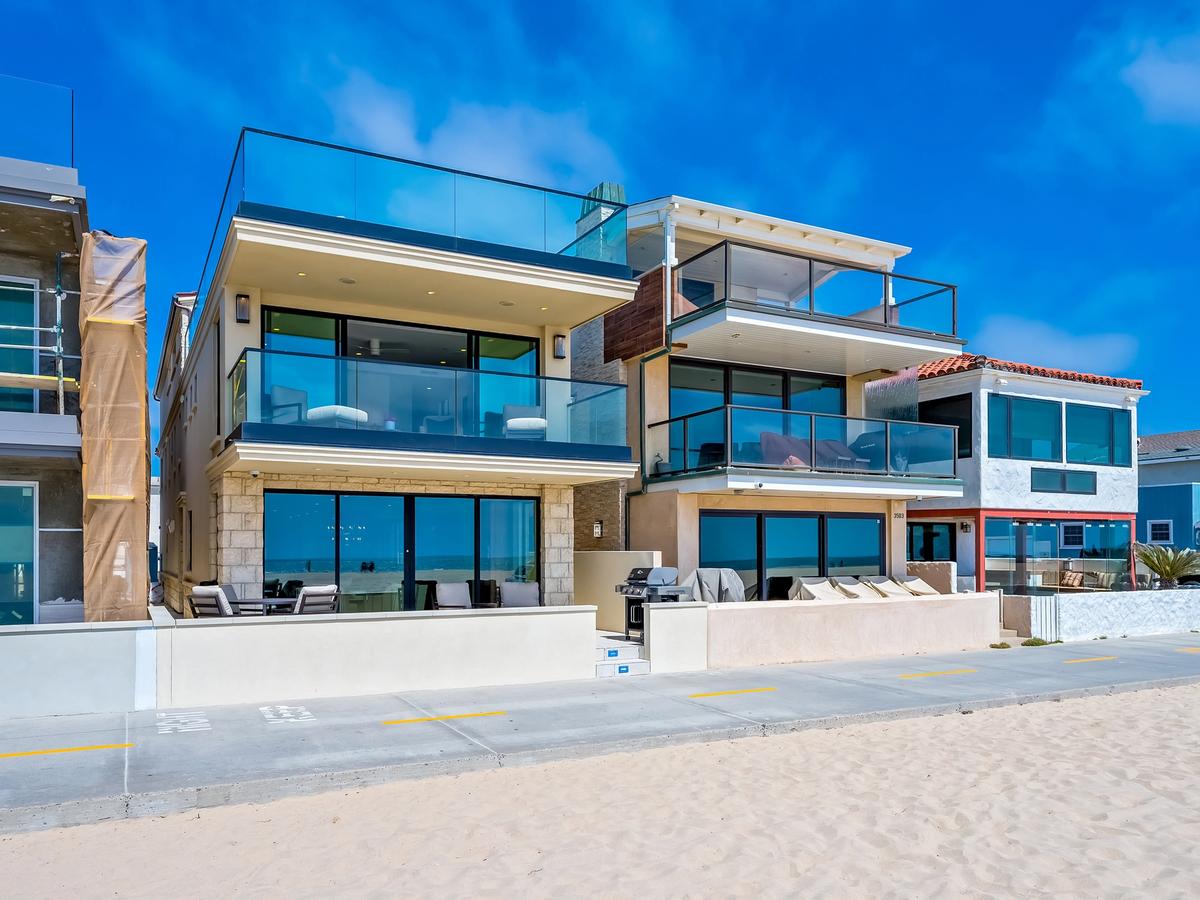 Modern beachfront vacation rental in Newport Beach, California with glass balconies, ocean views, and direct access to the sand and boardwalk.