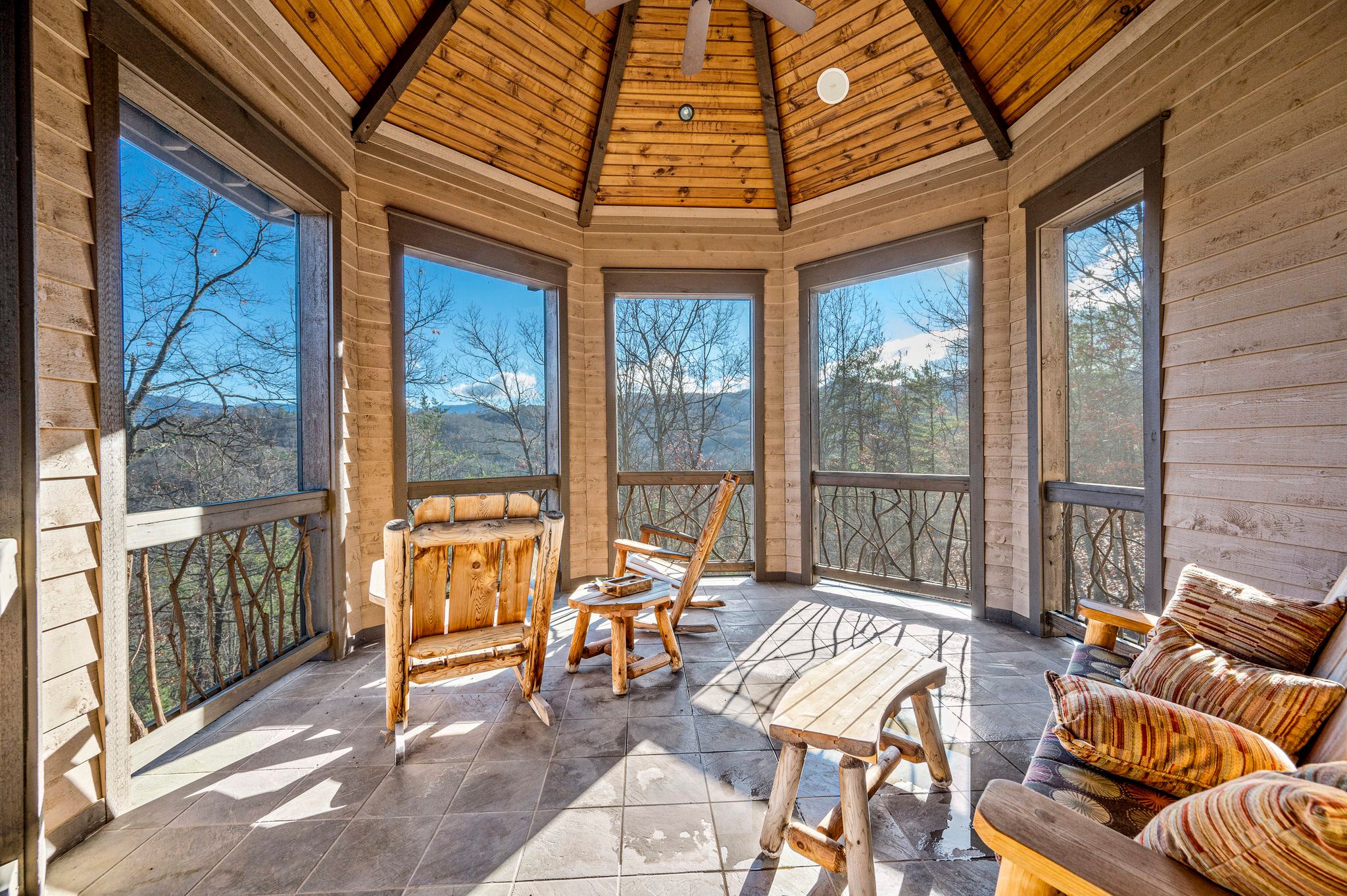 Two wooden rocking chairs in circular sunroom area of vacation rental
