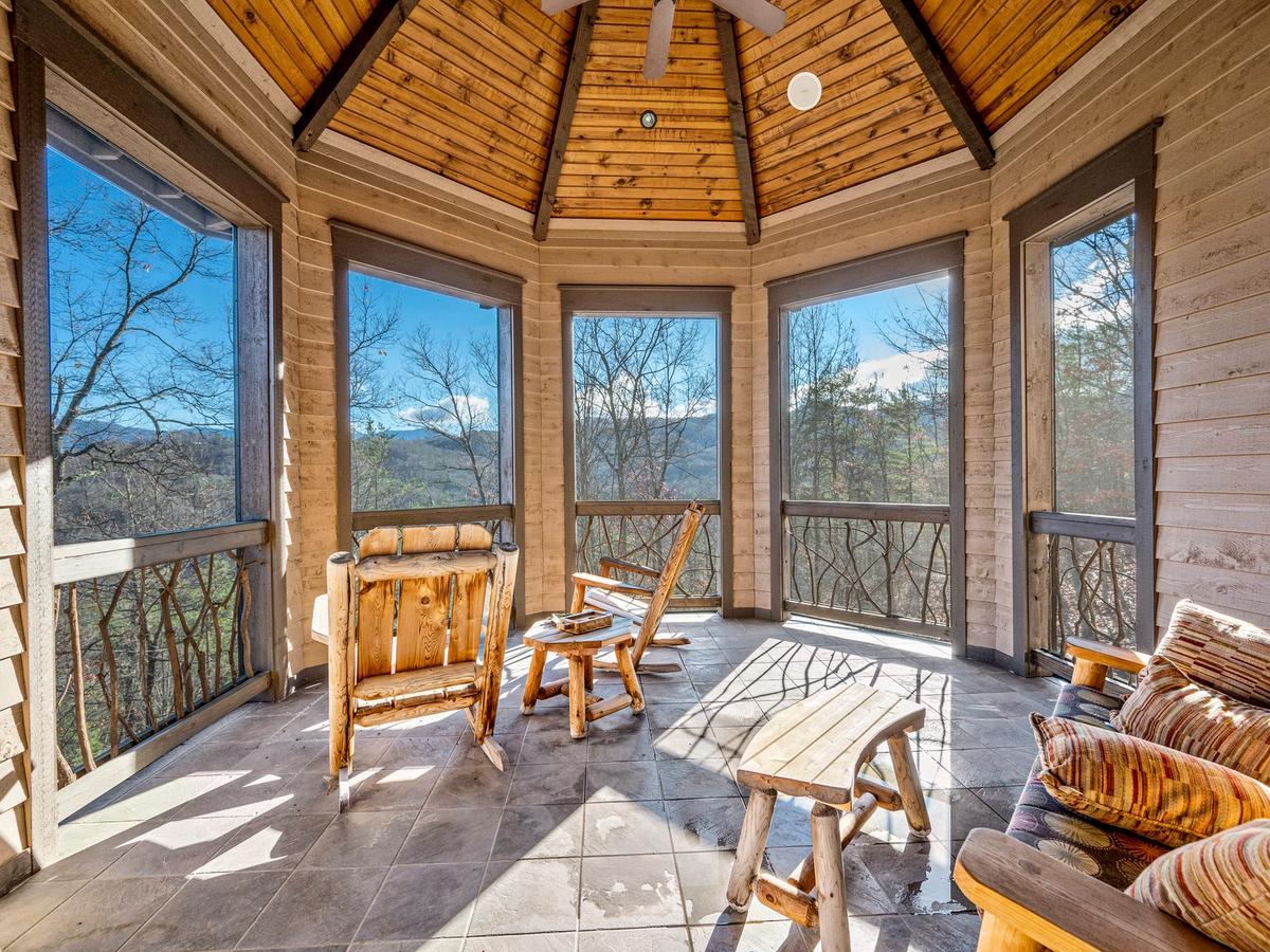 Two wooden rocking chairs in circular sunroom area of vacation rental