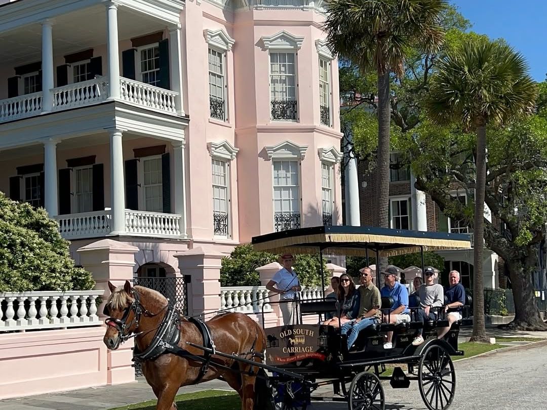 A scenic carriage tour by Old South Carriage Company rolls past a historic pink Charleston mansion, offering a charming glimpse into the city’s elegant past.