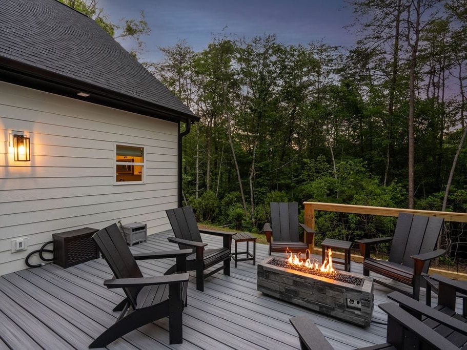 Stylish cabin deck with Adirondack chairs and a sleek fire table set against the trees. It’s a peaceful spot to wind down, chat under the stars, or relax after a day on the trails.