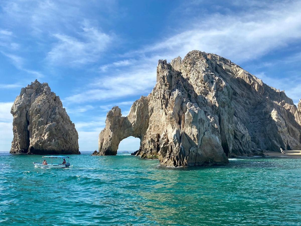 Rock arch in Los Cabos with people in small boat nearby it