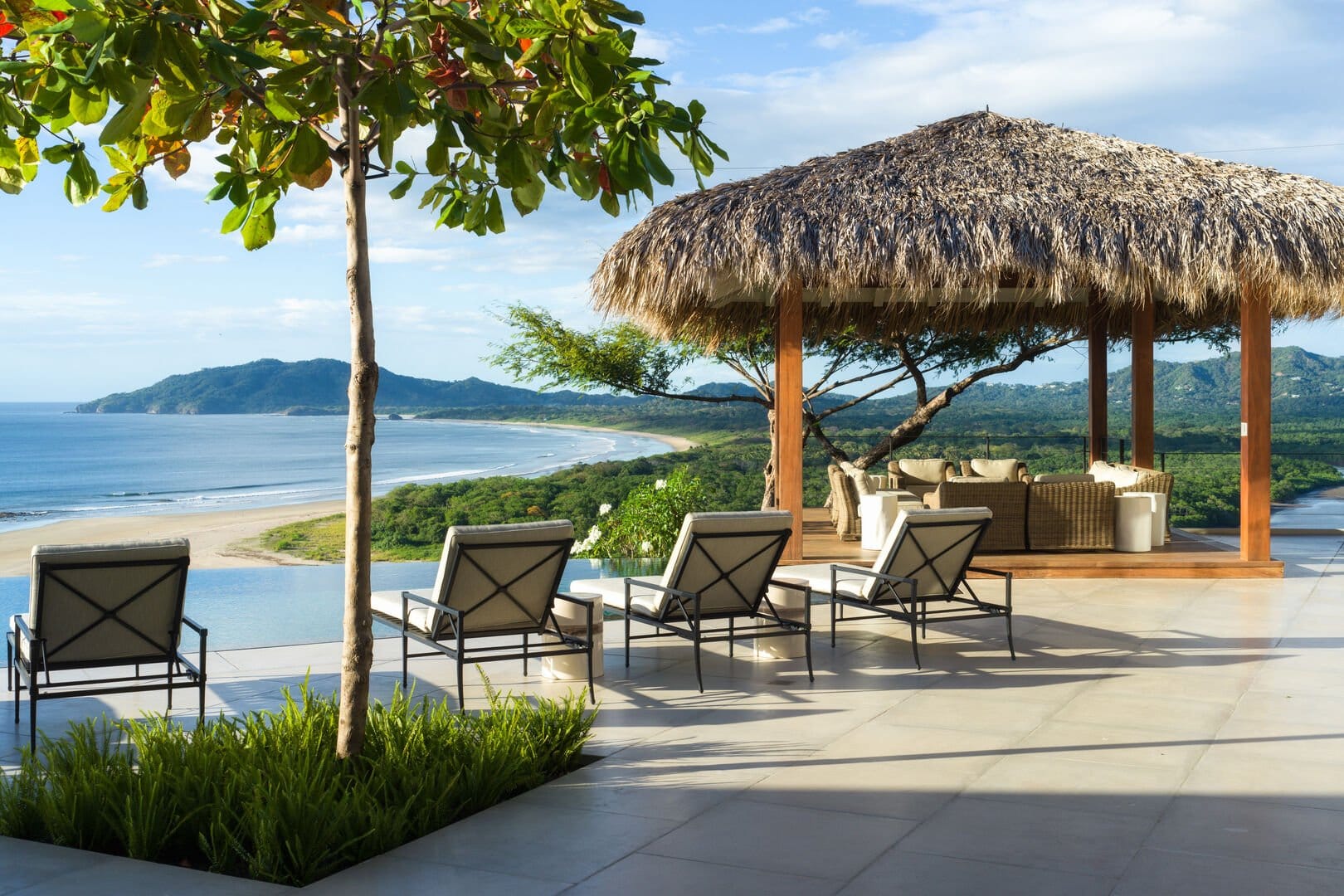 A beachfront villa in Tamarindo offers sweeping views of the Pacific Ocean with open-air lounges shaded by palm-thatched roofs. The serene coastal setting invites guests to relax in true Costa Rican style.