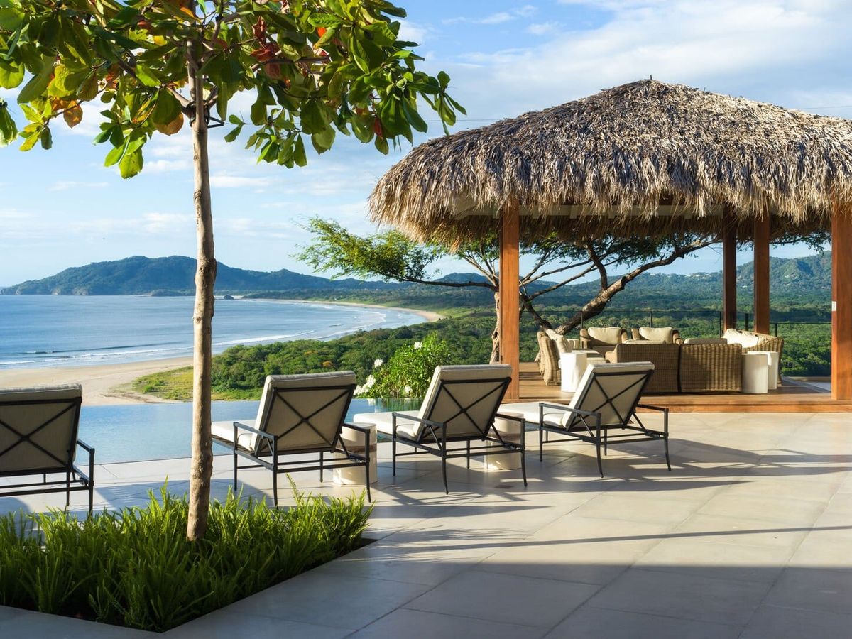 A beachfront villa in Tamarindo offers sweeping views of the Pacific Ocean with open-air lounges shaded by palm-thatched roofs. The serene coastal setting invites guests to relax in true Costa Rican style.