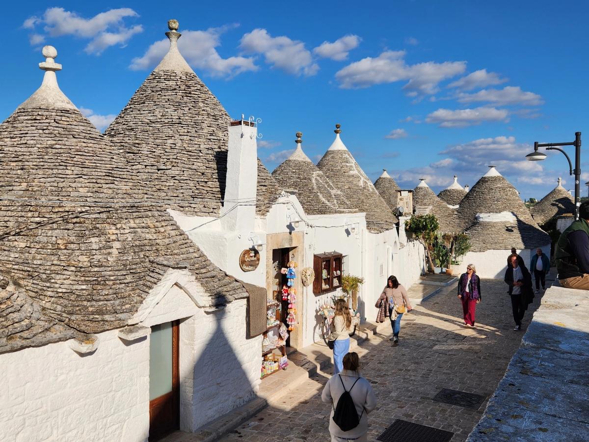 Visitors stroll through a charming street lined with unique local shops like Gustare Oils and Vinegars in Cape Cod. Small storefronts and bright displays make it a fun place to explore local flavors and gifts while walking through town. It captures the lively shopping culture of Cape Cod’s coastal villages.