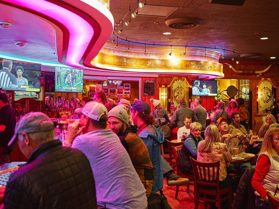 Guests gather around the bar at The Silver Dollar Showroom, enjoying drinks and live sports in a warm, vintage setting. This classic Jackson Hole venue blends old-west charm with live entertainment and social energy.