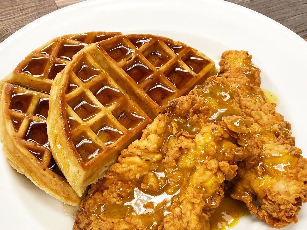 Crispy fried chicken paired with golden waffles and warm syrup on a white plate. A classic Southern combo that’s both sweet and savory.