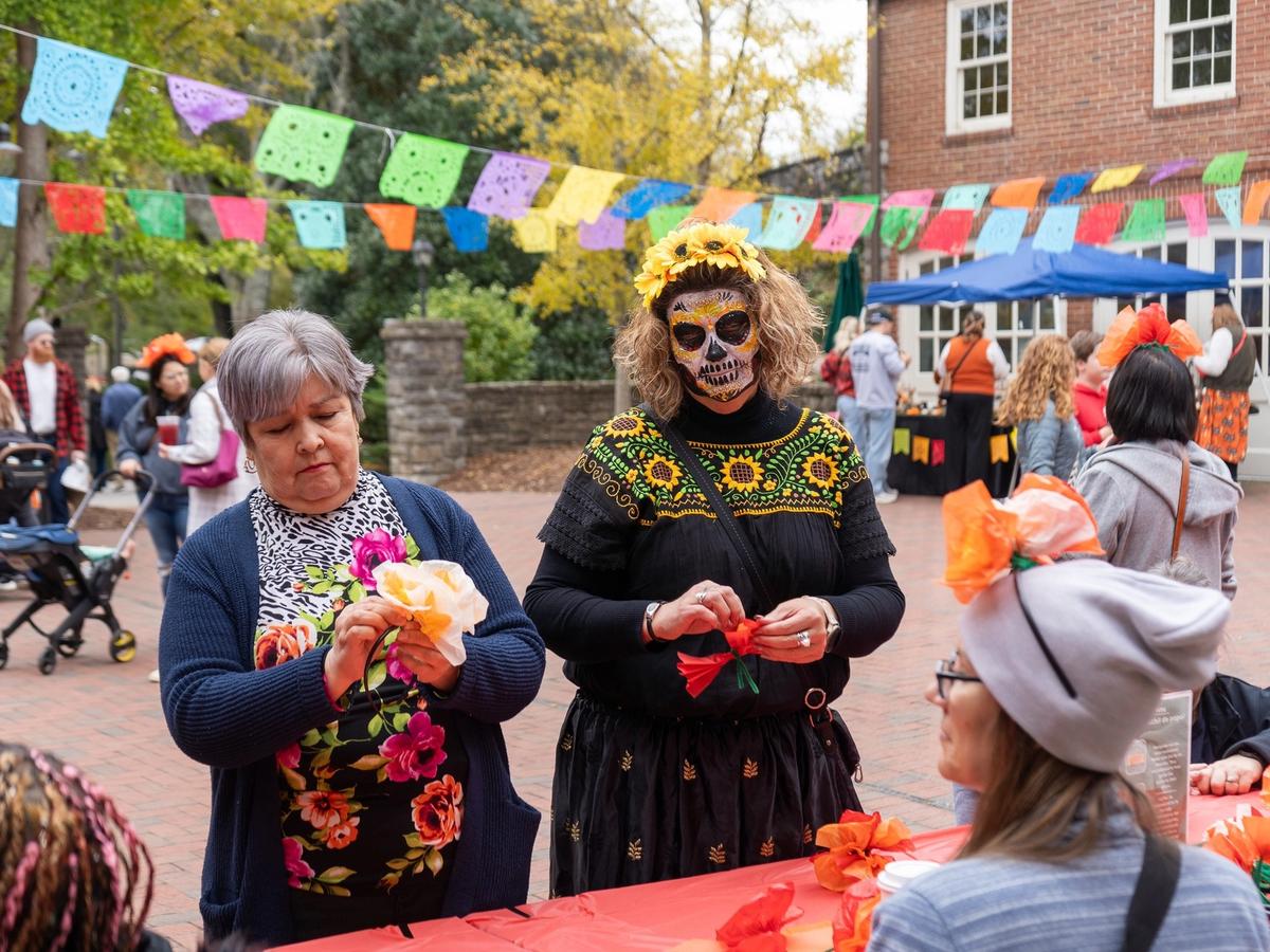 Crowds gather under rows of festival tents, enjoying drinks, food, and sunny weather at the Tennessee Beer, Wine, and Shine Festival. People chat, taste samples, and explore local vendors under the big shade trees. The whole scene has a lively, friendly vibe perfect for a fall day out.