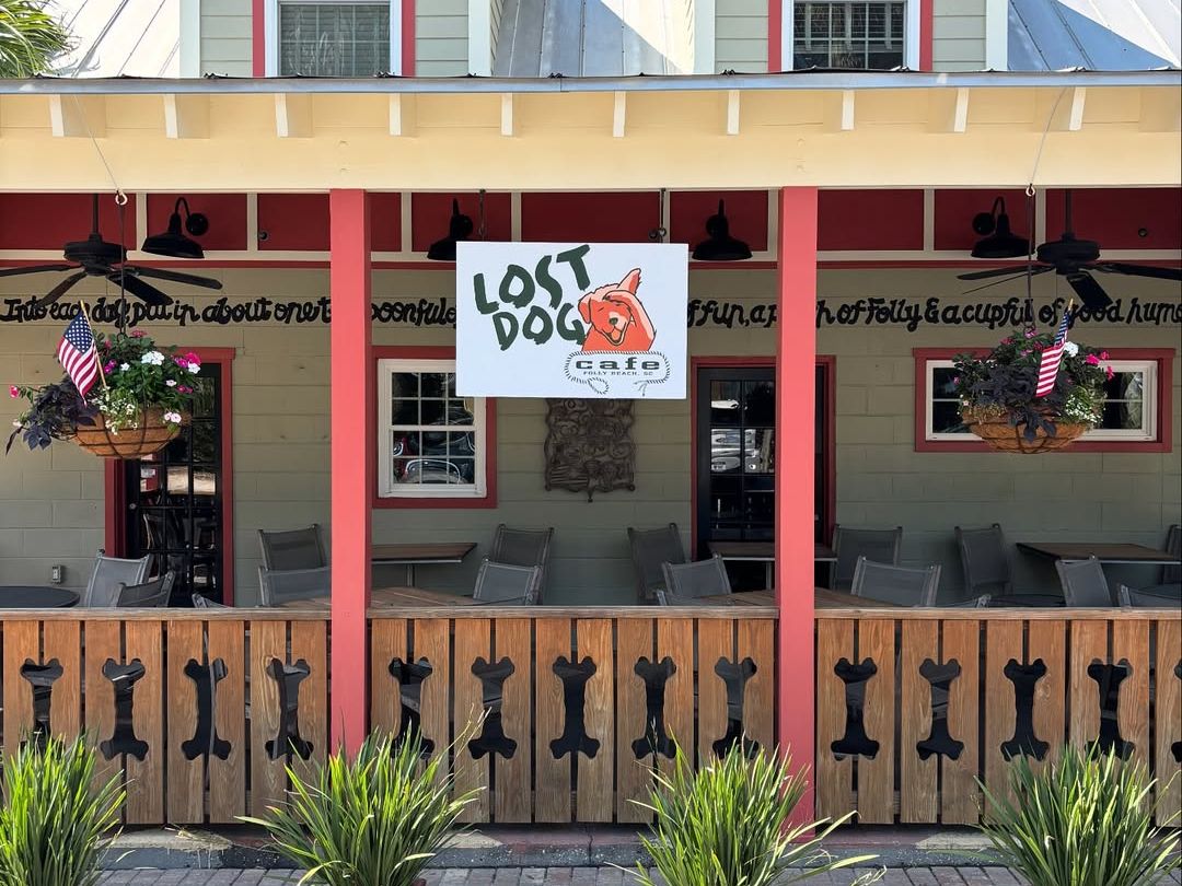 The Lost Dog Café in Folly Beach features a charming porch with dog bone railings and patriotic touches, making it a cozy and pet-friendly breakfast spot loved by locals and visitors.