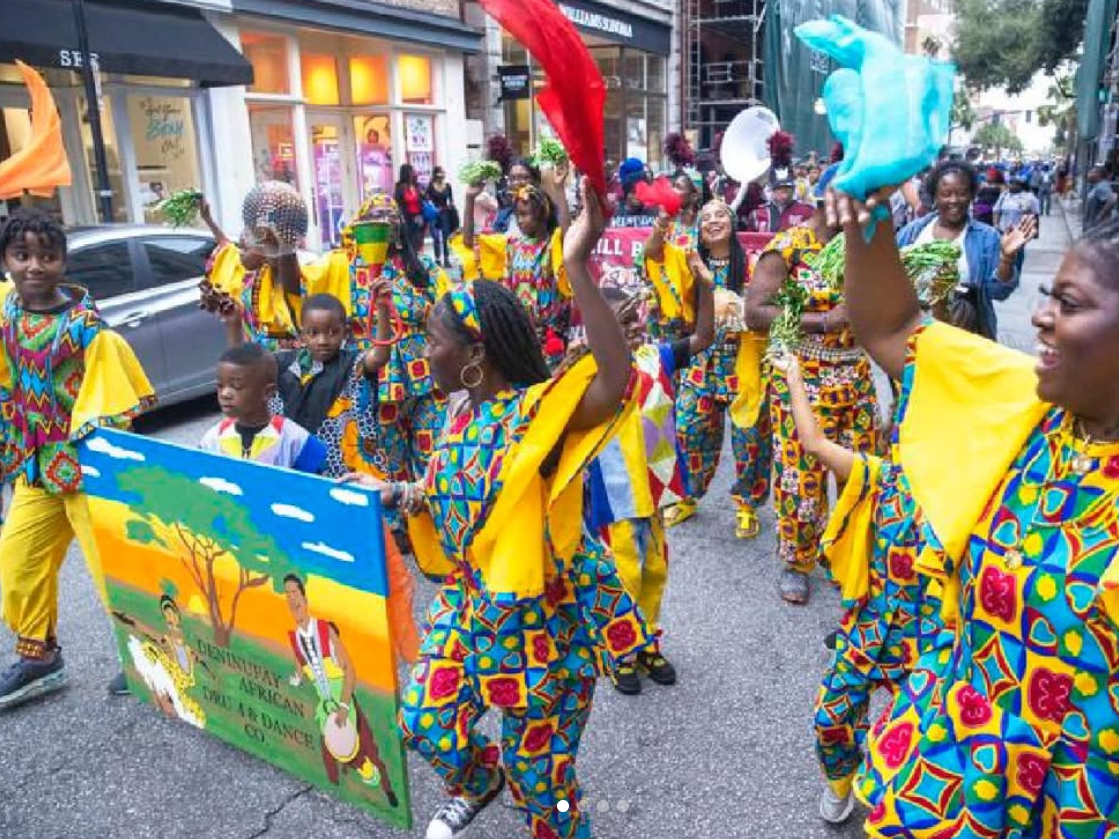 Parade of women and children holding art painting and waving colorful cloth in Caribbean color clothing