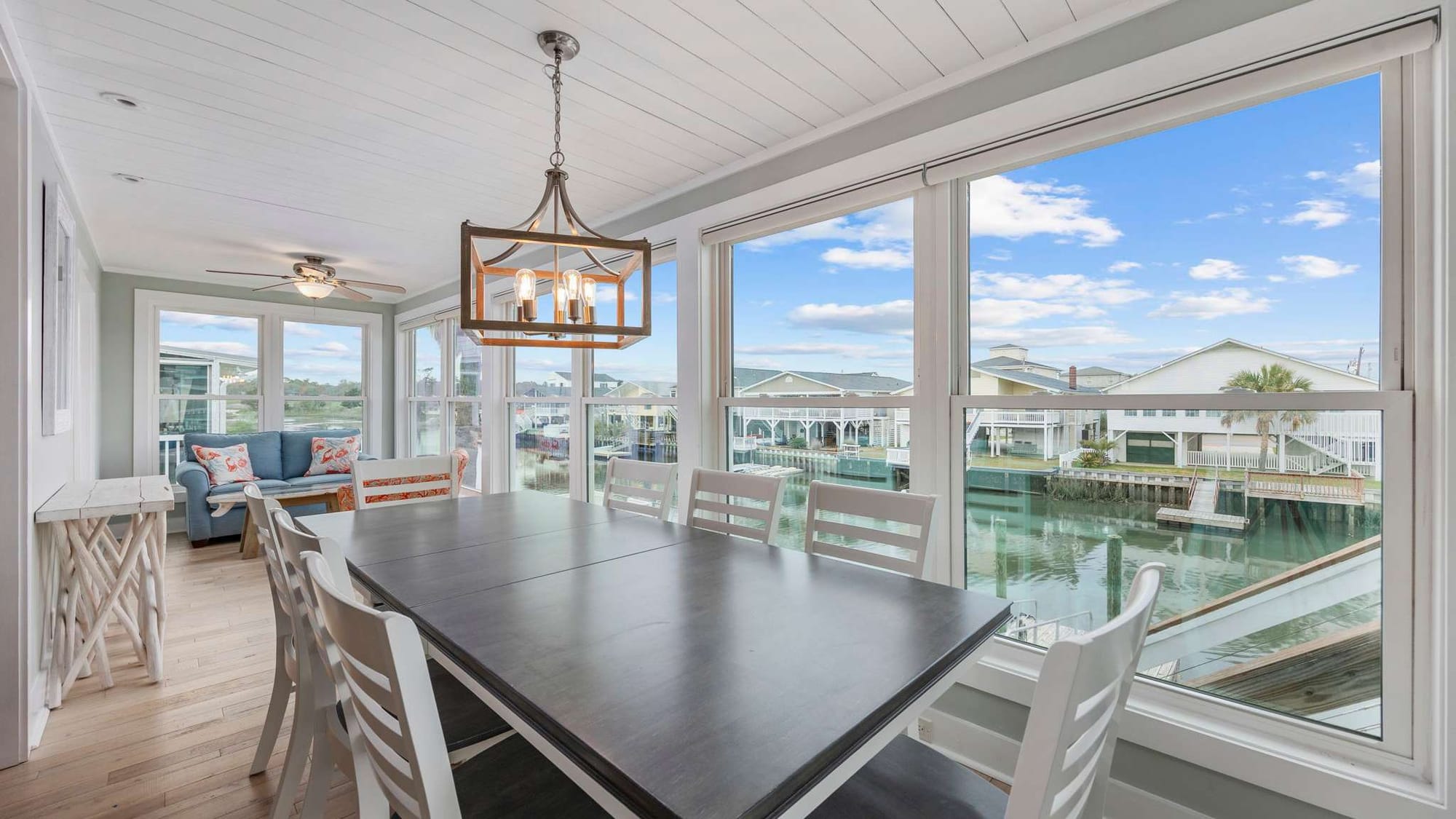Sun-filled dining area with large windows overlooks peaceful waterfront canal views. This bright space is perfect for enjoying meals together while taking in scenic coastal surroundings.