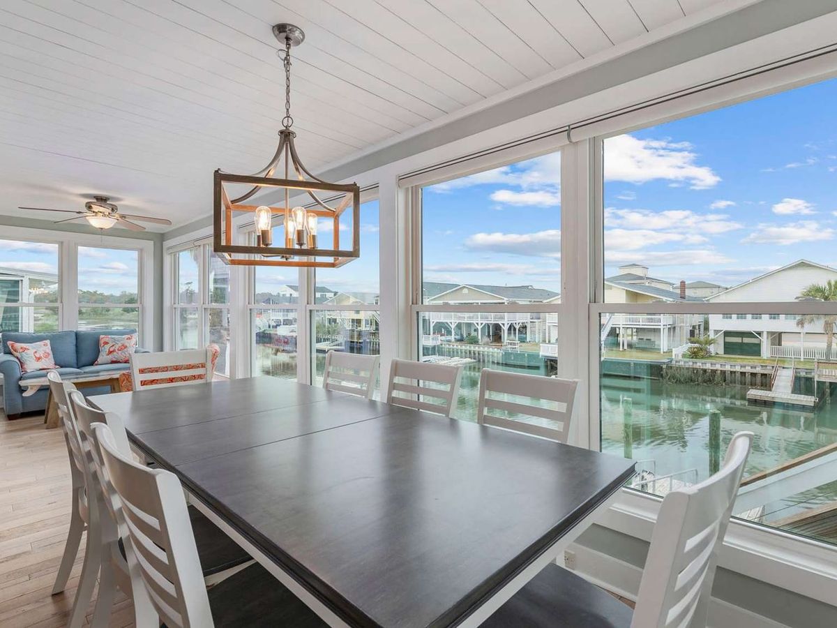 Sun-filled dining area with large windows overlooks peaceful waterfront canal views. This bright space is perfect for enjoying meals together while taking in scenic coastal surroundings.
