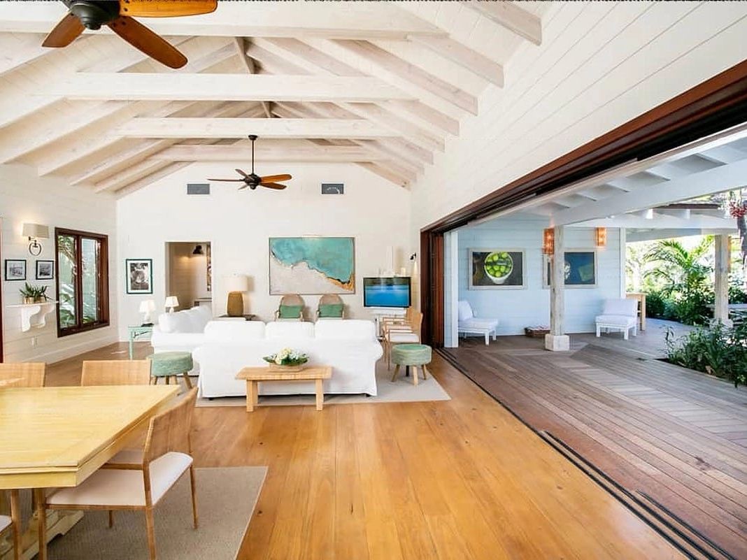 Elegant villa with a pool that flows right into the turquoise sea, surrounded by palm trees and sunny skies. It’s a dreamy spot for luxury lovers and beachgoers.