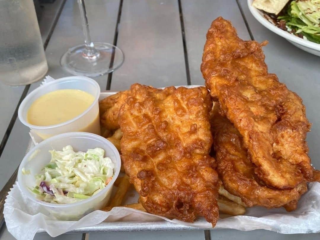 Crispy shrimp tacos topped with bright pink slaw and served with fries and a cocktail on a breezy patio. A perfect island lunch with a tropical touch and refreshing drinks.