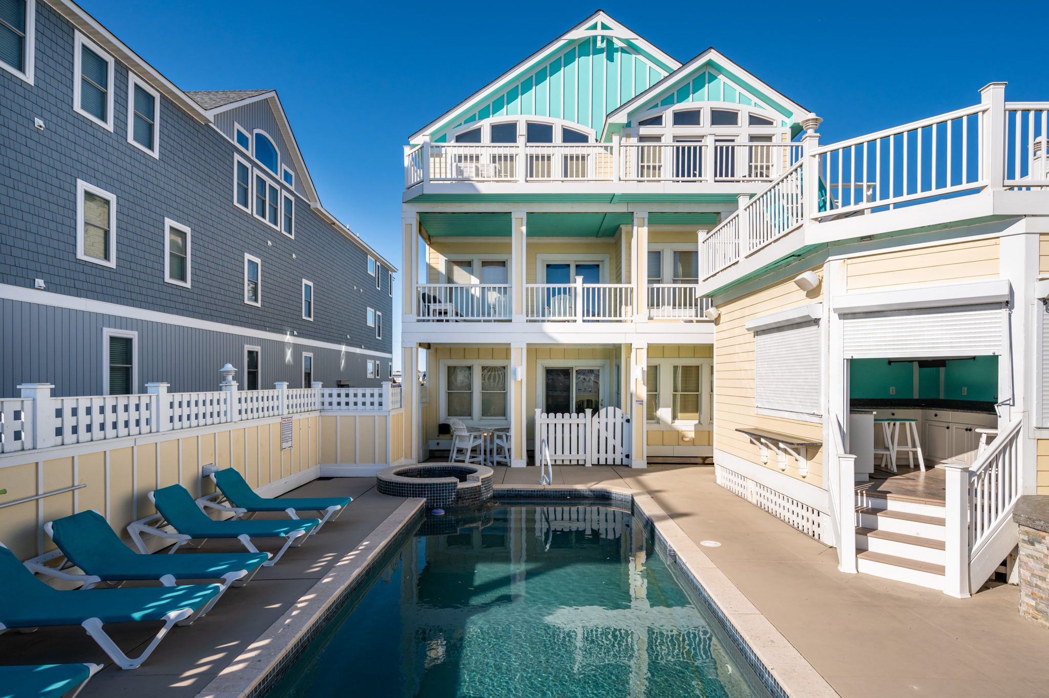 Private pool at turquoise and yellow home with rooftop lounge area