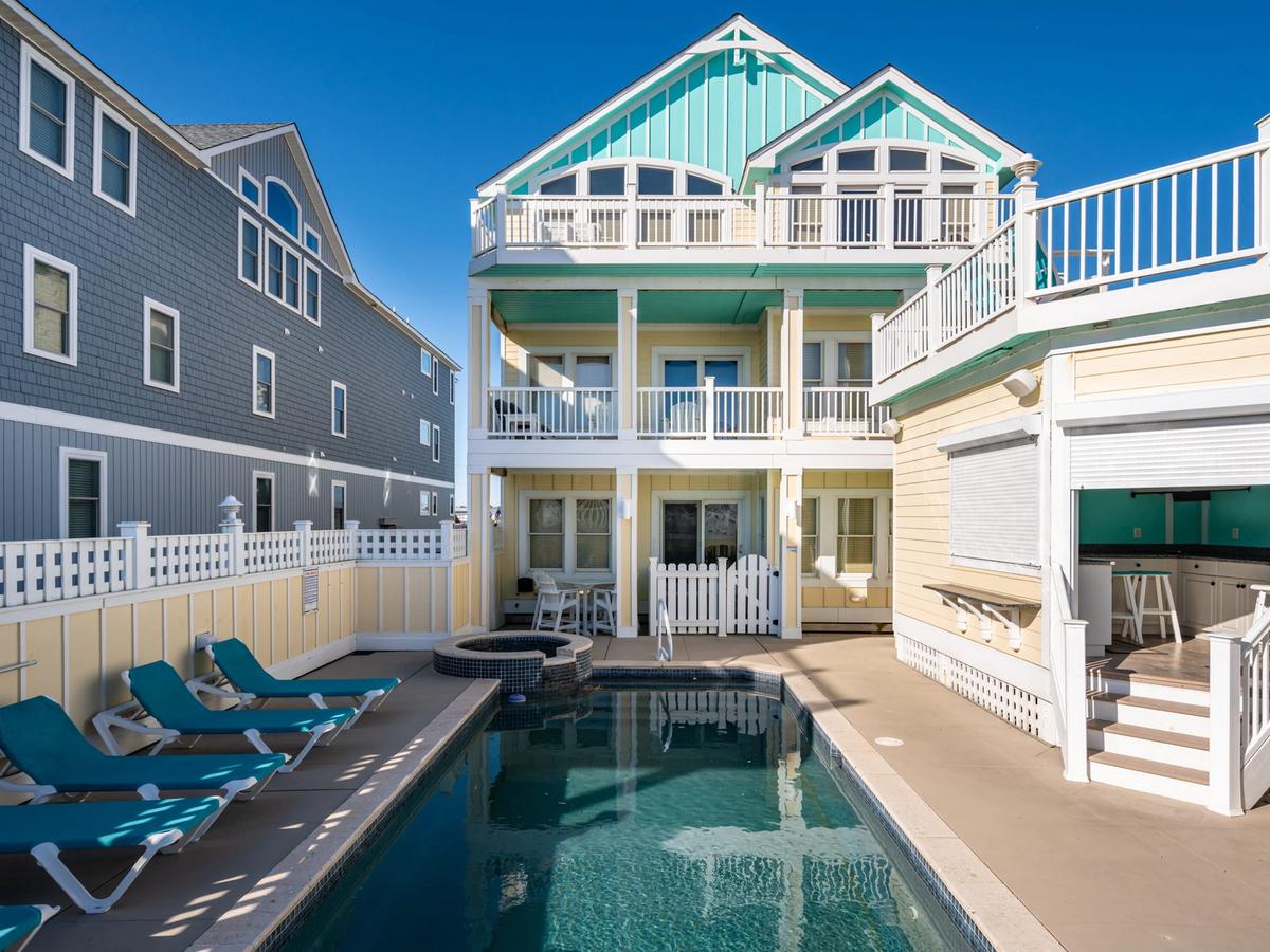 Private pool at turquoise and yellow home with rooftop lounge area