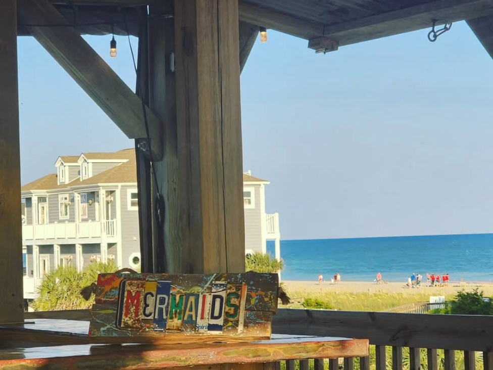 Mermaids sign on wooden bar top at restaurant with beach views