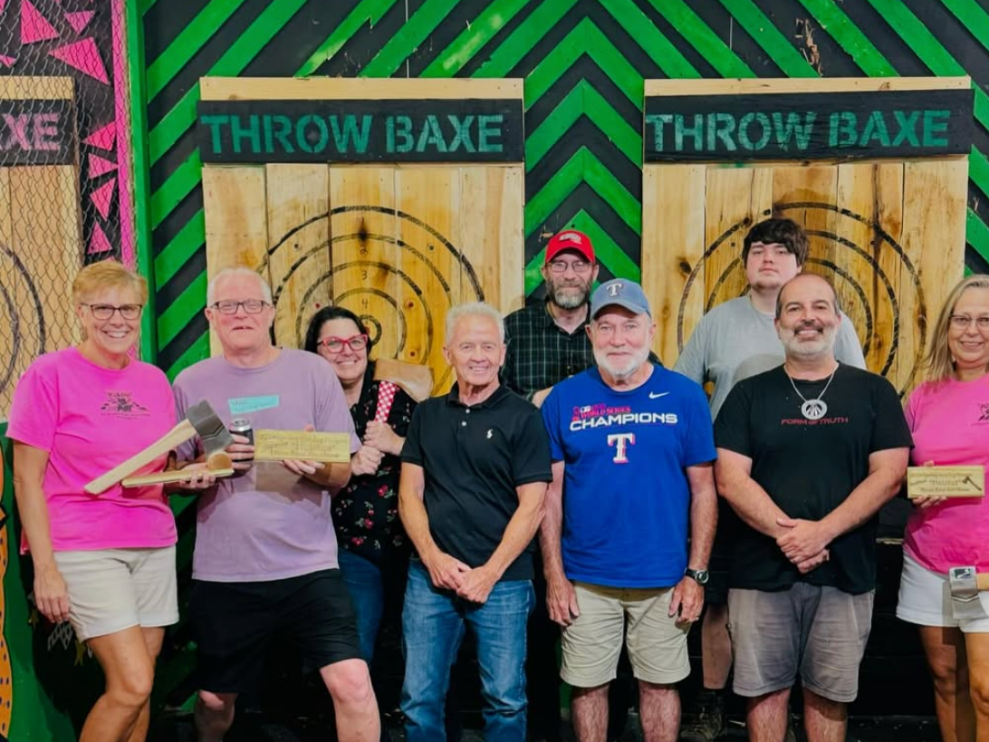 Group of people with axe throwing wooden boards in the back and neon green striped wall
