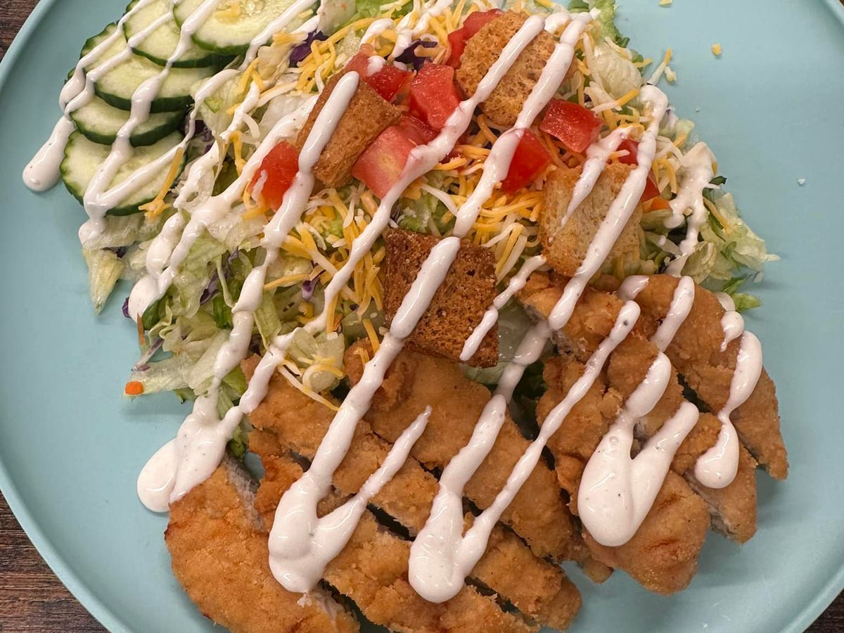 Crispy chicken tenders over a bed of shredded salad, cucumbers, cheese, and croutons, topped with creamy ranch dressing. A filling and fresh salad made with comfort food flavor.