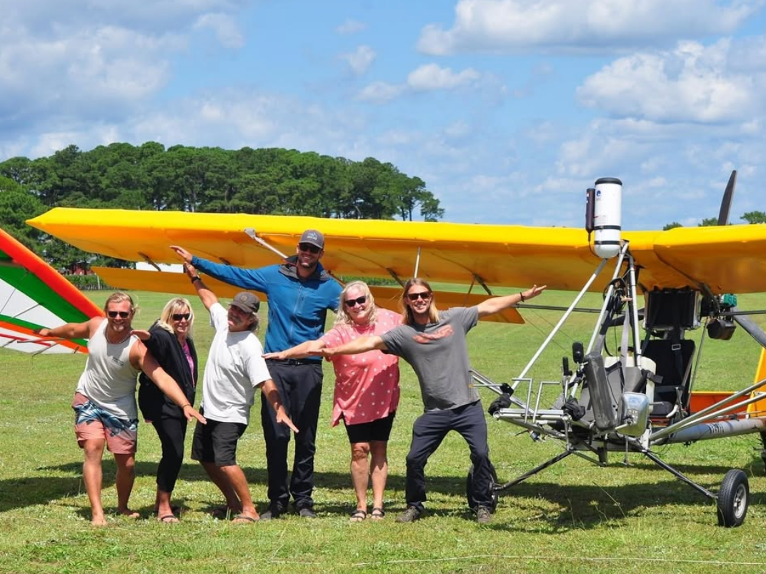People standing in front of old plane with instructor