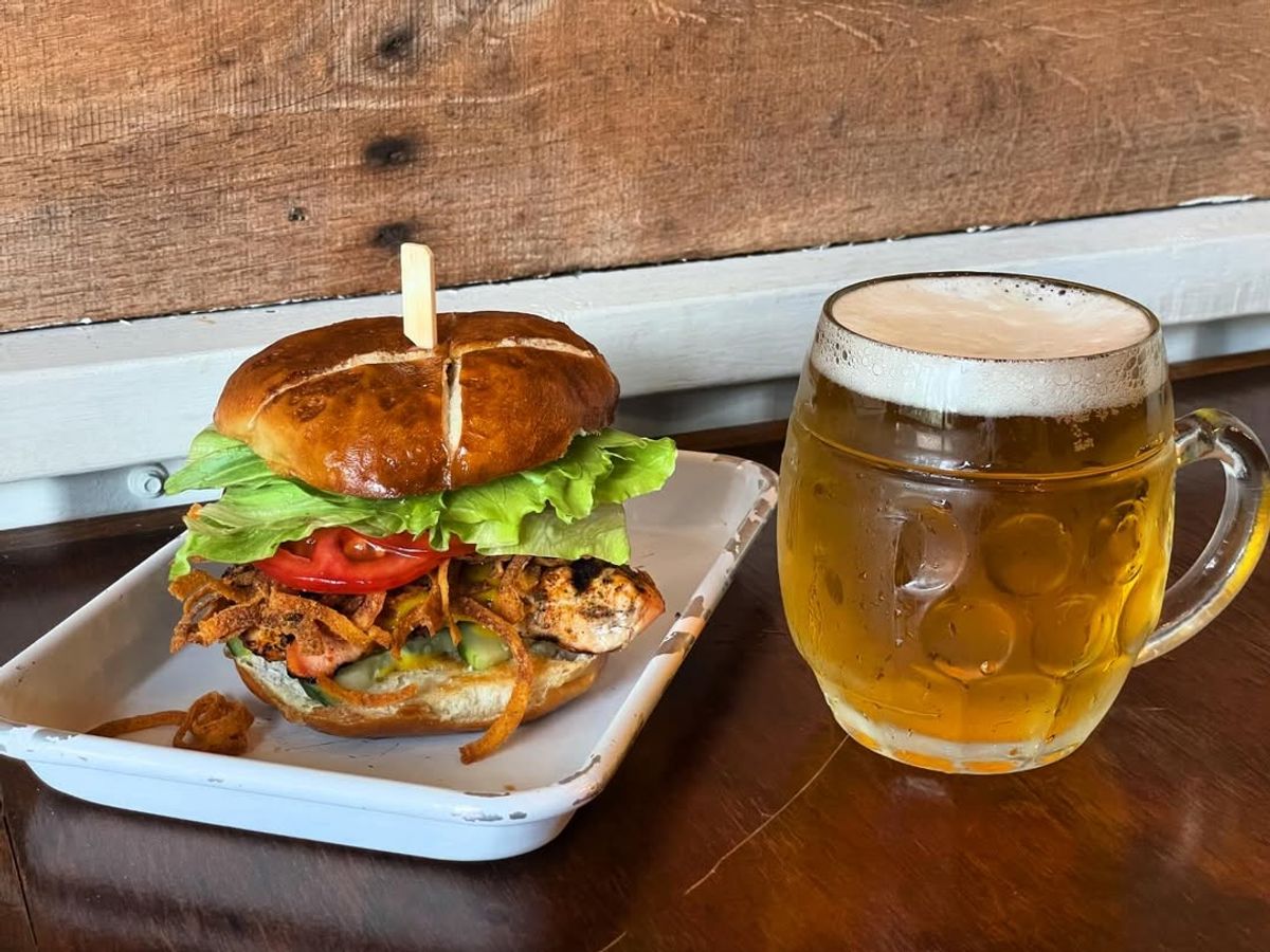 A juicy grilled chicken sandwich sits next to a frosty beer mug at Terra Nova Beer Co. This Asheville favorite mixes great food and small-batch beers for a relaxed neighborhood experience.