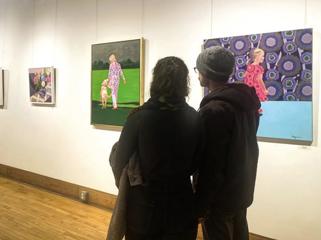 A couple stands closely together in an art gallery, viewing colorful paintings on the wall, including a portrait of a woman walking a dog and another against a bold patterned background.