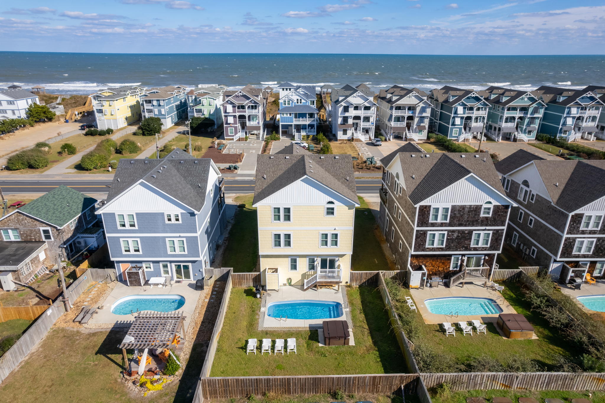 Aerial view of three homes side by side with private pools