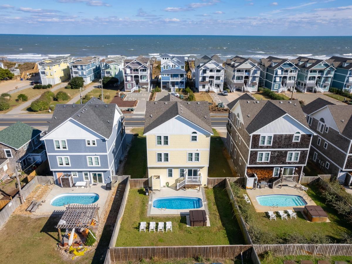 Aerial view of three homes side by side with private pools