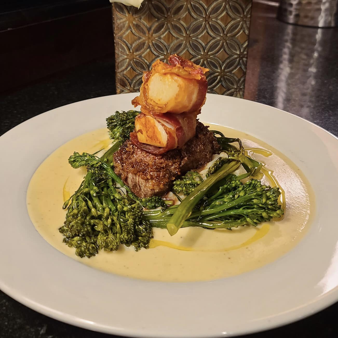 A bowl of creamy seafood pasta topped with herbs and vegetables sits on a restaurant table with a cocktail in the background. The dish looks rich and comforting, perfect for a relaxed dinner after a day of exploring Cape Cod. Restaurants like this are known for serving classic New England flavors with a modern touch.