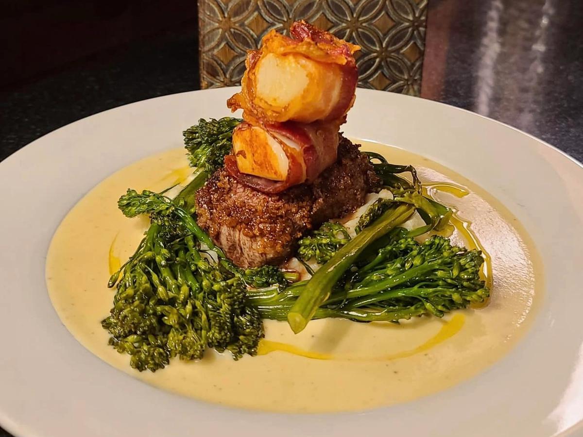 A bowl of creamy seafood pasta topped with herbs and vegetables sits on a restaurant table with a cocktail in the background. The dish looks rich and comforting, perfect for a relaxed dinner after a day of exploring Cape Cod. Restaurants like this are known for serving classic New England flavors with a modern touch.