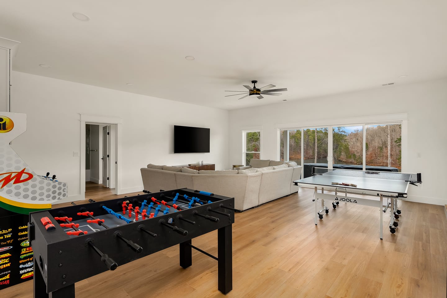 Game room with arcade game, tan white couch, ping pong table, and foosball table
