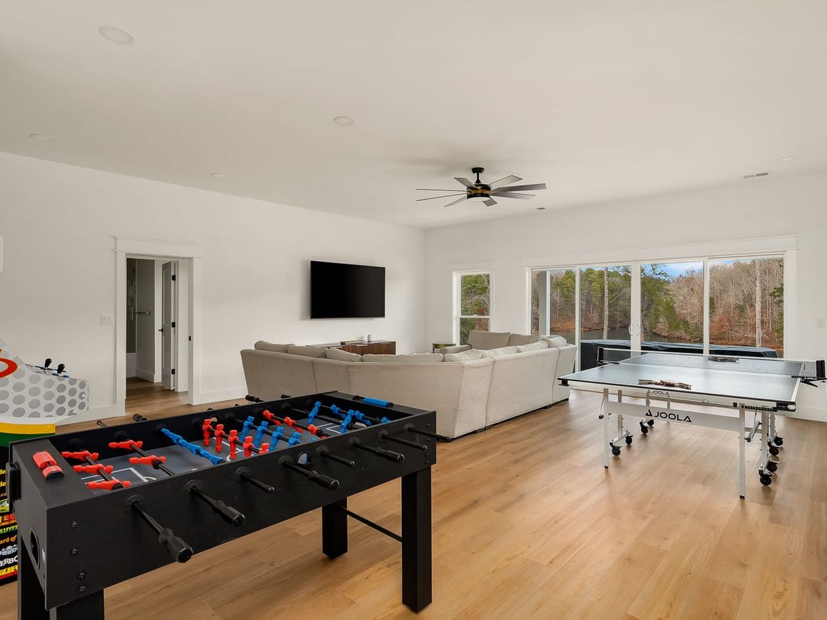 Game room with arcade game, tan white couch, ping pong table, and foosball table