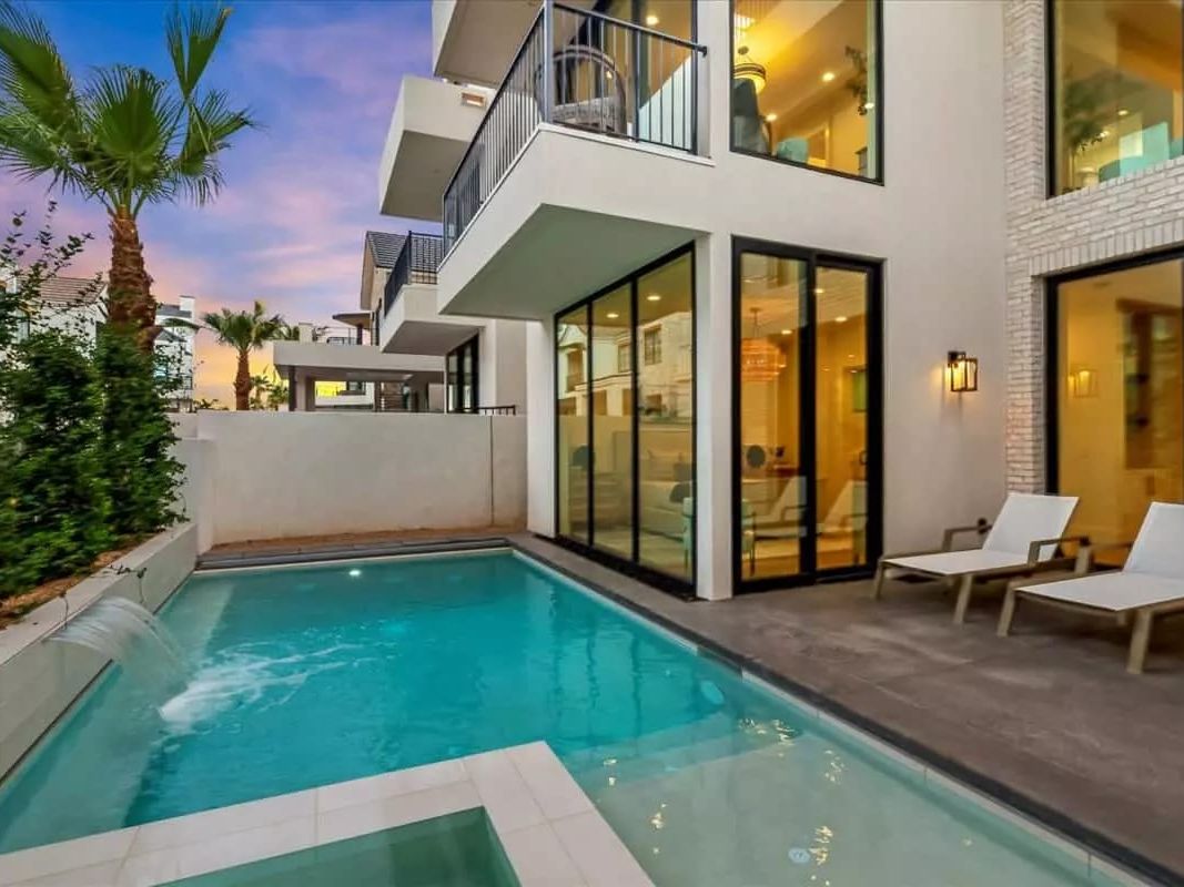 A contemporary desert villa in St. George with sleek architecture, a private pool, and palm-lined surroundings. This stylish retreat glows beautifully under the warm sunset sky.