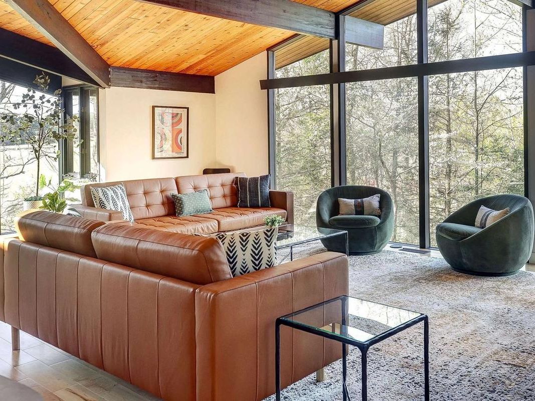 A beautiful screened-in patio opens to a stone path leading to a serene garden pool surrounded by lounge chairs. With cozy outdoor seating and a white pergola, this space is perfect for relaxing in all seasons.