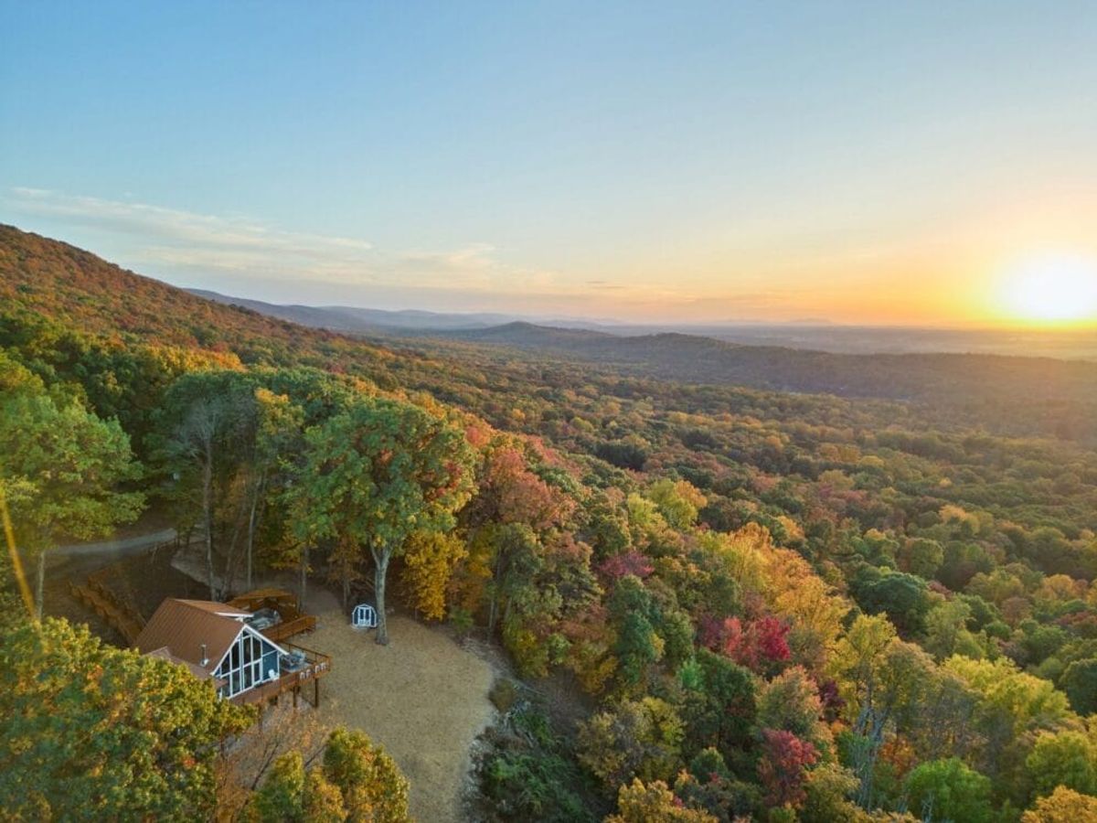 Secluded mountain cabin surrounded by colorful fall foliage and wide scenic mountain views at sunrise. The private location offers a peaceful retreat where you can enjoy nature and stunning seasonal landscapes.
